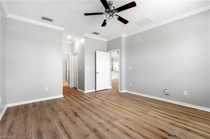 Unfurnished bedroom featuring baseboards, wood finished floors, visible vents, and crown molding