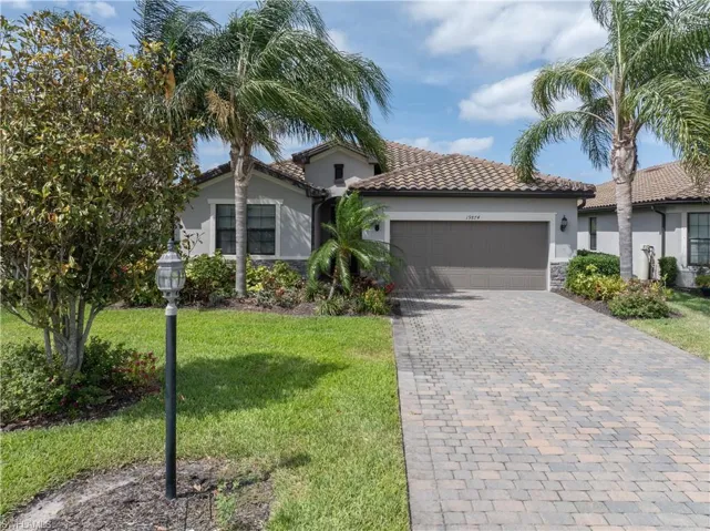 Mediterranean / spanish house with stucco siding, an attached garage, a tile roof, decorative driveway, and a front yard
