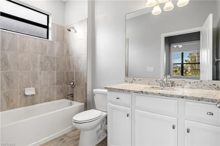 Bathroom with wood finished floors, bathing tub / shower combination, vanity, and toilet
