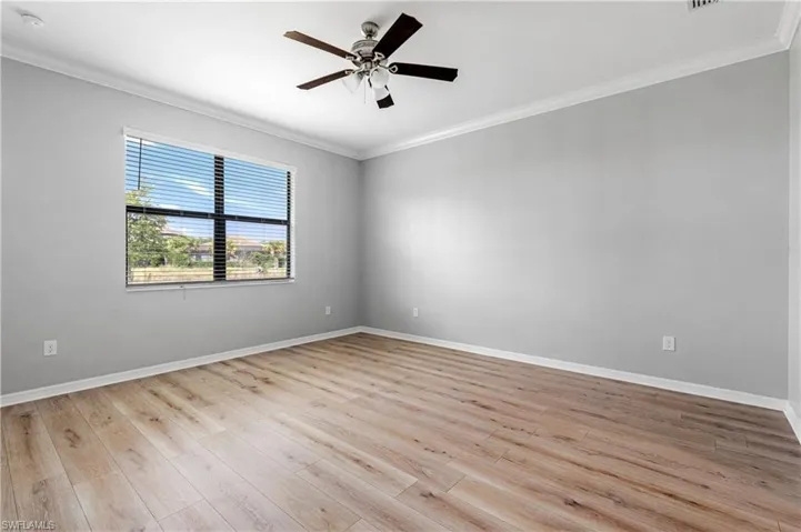 Spare room with baseboards, light wood-style floors, and crown molding