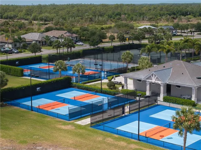 View of basketball court with fence, a wooded view, and a tennis court