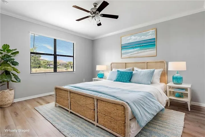 Bedroom with baseboards, ornamental molding, light wood-style floors, and a ceiling fan