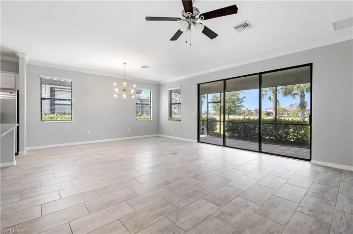 Unfurnished room featuring crown molding, ceiling fan with notable chandelier, visible vents, and plenty of natural light
