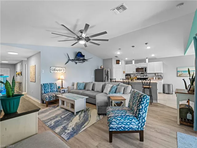 Living room with ceiling fan, light wood-style floors, lofted ceiling, and recessed lighting