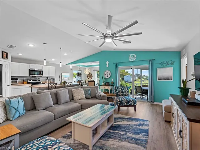 Living room with wood finished floors, vaulted ceiling, and a ceiling fan