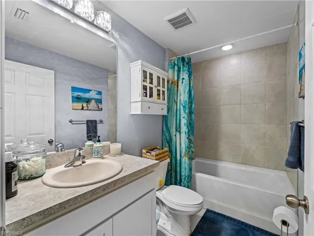 guest Bathroom featuring shower / bathtub combination with curtain, vanity, and tile patterned flooring