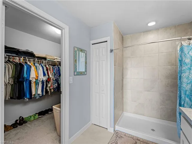 Full bathroom featuring a shower stall, a spacious closet, vanity, and light tile patterned floors