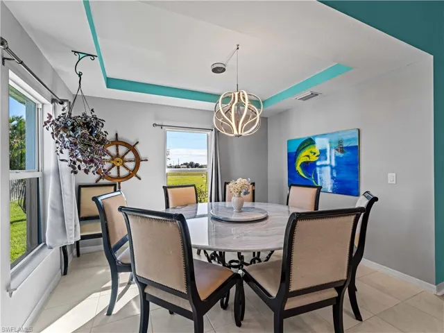 Dining area featuring a tray ceiling, a chandelier, and light tile patterned floors