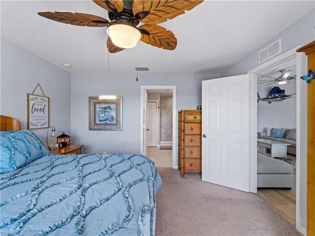 Bedroom with light carpet, ceiling fan, and ensuite bathroom