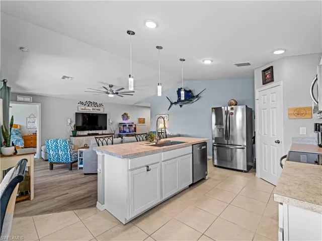 Kitchen featuring light countertops, appliances with stainless steel finishes, ceiling fan, open floor plan, and lofted ceiling