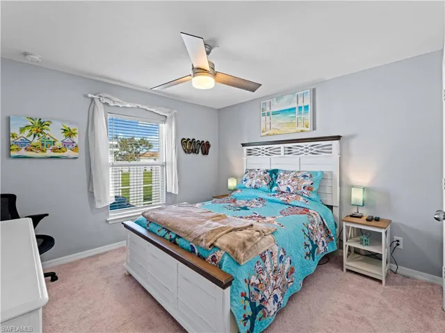 Bedroom with ceiling fan, light colored carpet, and an office area