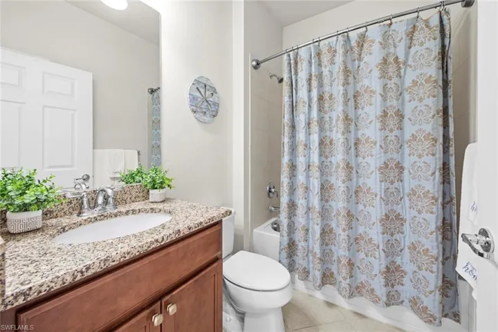 Bathroom featuring shower / bath combination with curtain, vanity, and light tile patterned floors