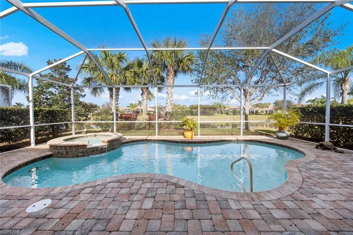 View of swimming pool featuring a sunroom, a water view, a patio area, and a pool with connected hot tub