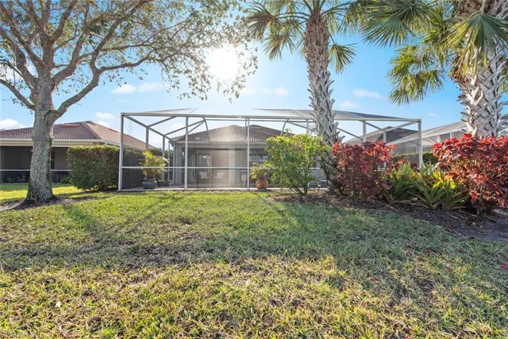 View of grassy yard with a sunroom and a lanai