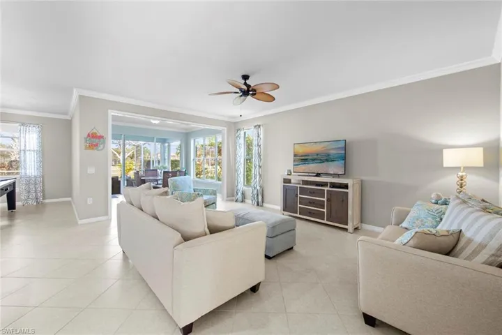 Living room with crown molding, light tile patterned flooring, and ceiling fan
