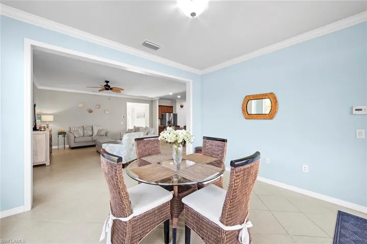 Dining room with ornamental molding, light tile patterned floors, and a ceiling fan