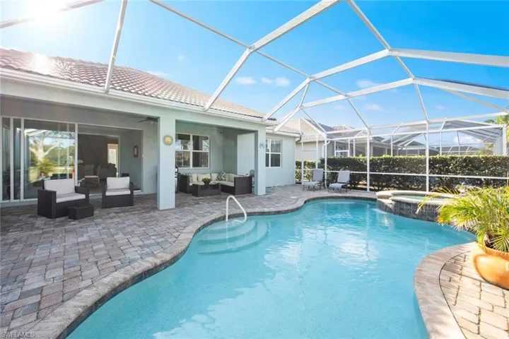 View of swimming pool featuring a patio, a sunroom, an outdoor hangout area, a lanai, and a pool with connected hot tub