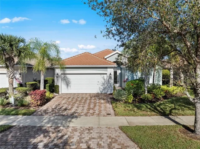 View of front of property featuring stucco siding, an attached garage, decorative driveway, a tiled roof, and a front lawn