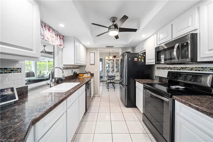 Kitchen featuring white cabinets, ceiling fan with  stainless steel appliances