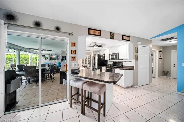 Kitchen featuring stainless steel appliances, white cabinetry, a kitchen breakfast bar, kitchen peninsula, and ceiling fan