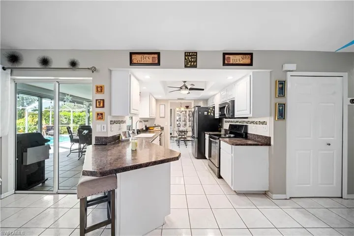 Kitchen with white cabinets, appliances with stainless steel finishes, sink, kitchen peninsula, and ceiling fan