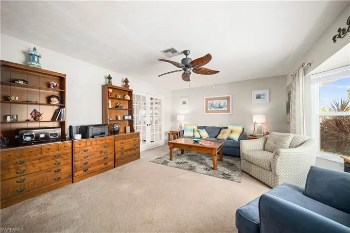 Carpeted living room featuring ceiling fan and french doors