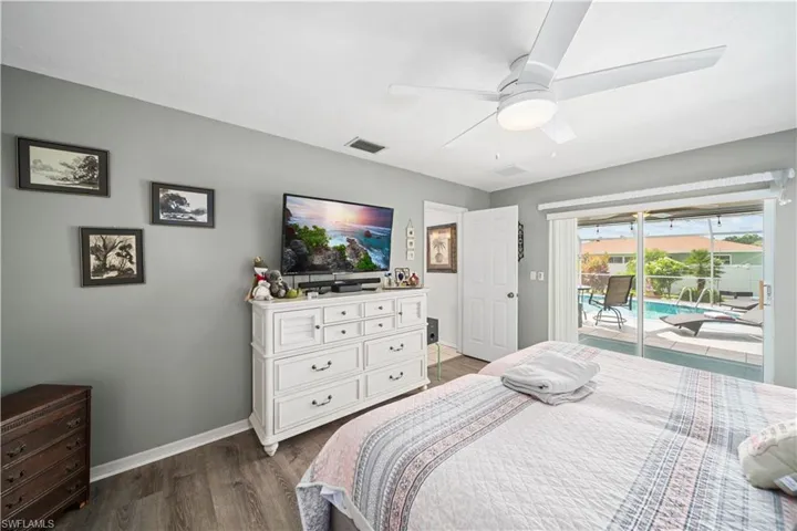 Primary bedroom with tiled plank flooring and view of the pool