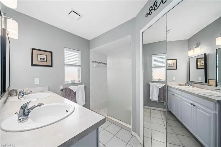 Bathroom with vanity, tiled shower, and tile patterned floors