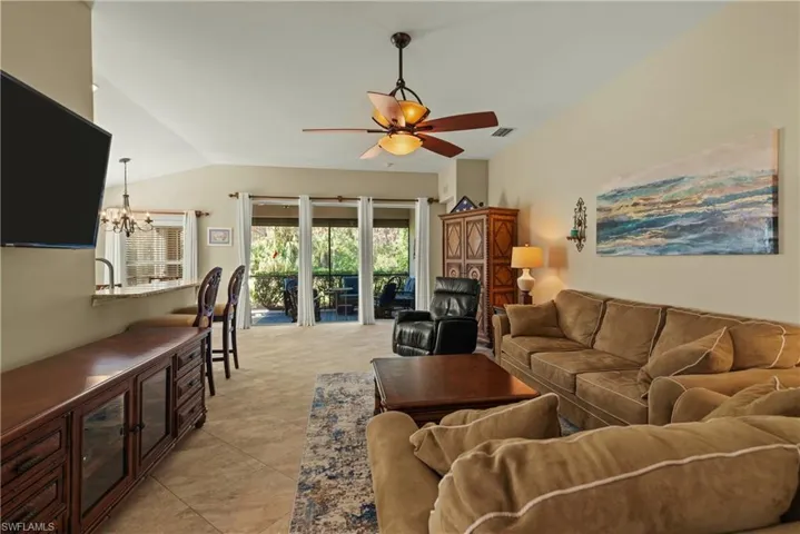 Living room featuring a chandelier, a ceiling fan, and lofted ceiling
