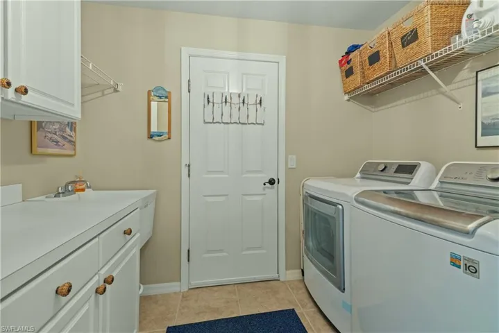 Laundry area featuring light tile patterned flooring and washing machine and dryer