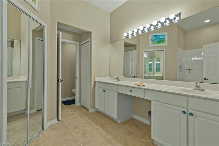Full bath with double vanity, light tile patterned floors, and a shower