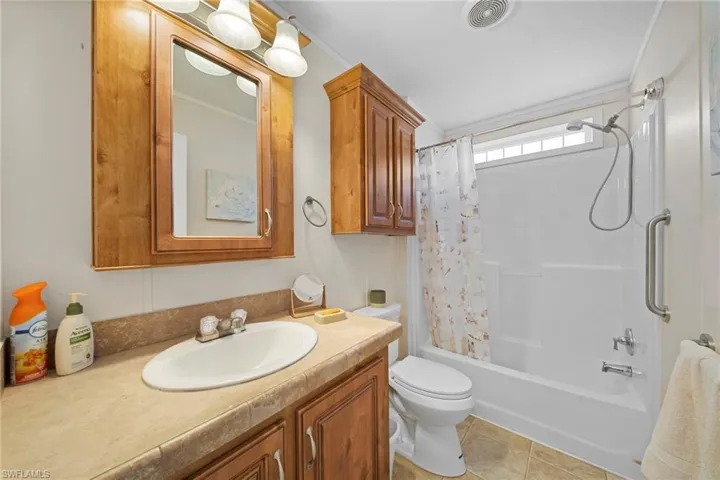 Bathroom featuring a light wood-finish vanity with a single basin, a matching mirrored medicine cabinet, and overhead sconce lighting