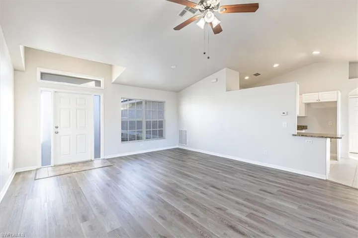 Unfurnished living room featuring lofted ceiling, light wood-type flooring, and a ceiling fan