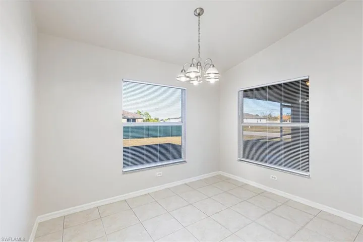 Unfurnished dining area featuring a chandelier, vaulted ceiling, and light tile patterned floors