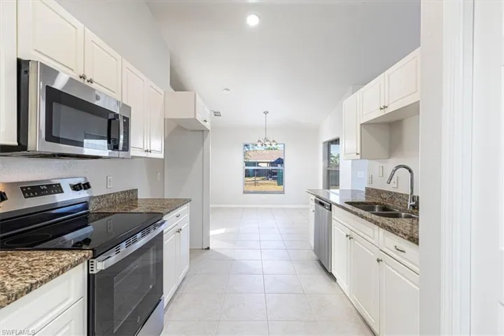 Kitchen featuring appliances with stainless steel finishes, dark stone countertops, light tile patterned floors, white cabinets, and recessed lighting