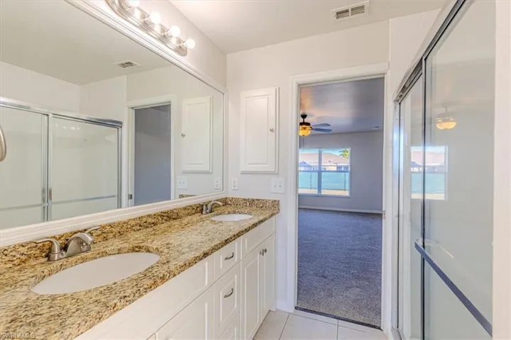 Bathroom featuring a shower stall, double vanity, light carpet, and light tile patterned floors