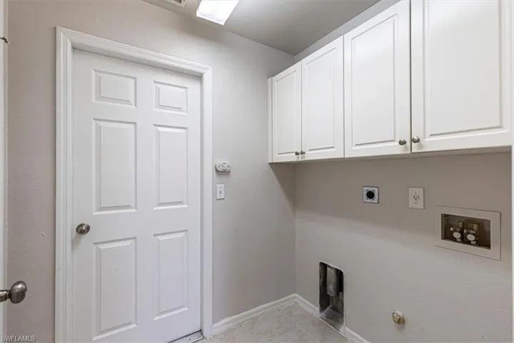 Washroom with gas dryer hookup, electric dryer hookup, washer hookup, cabinet space, and light tile patterned floors