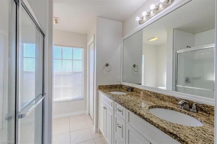Bathroom featuring a stall shower, double vanity, and light tile patterned flooring