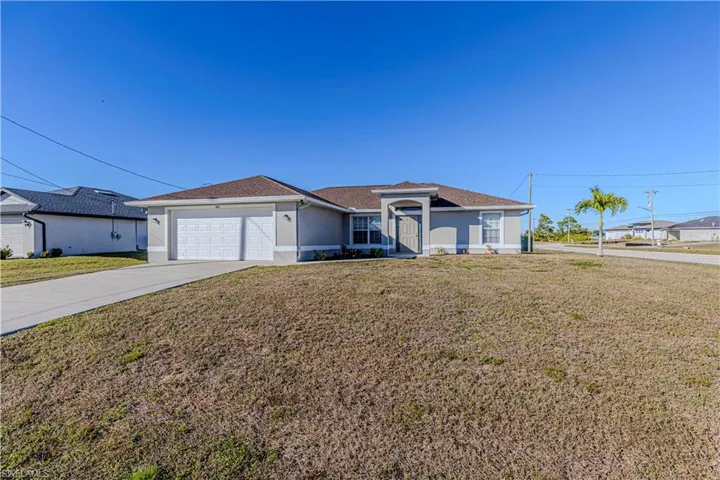 Ranch-style home featuring a front yard, concrete driveway, stucco siding, and an attached garage