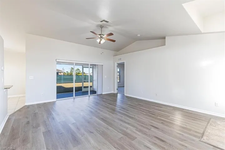 Empty room featuring light wood-style floors, vaulted ceiling, and ceiling fan