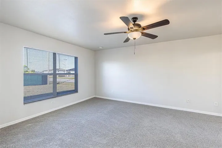 Carpeted empty room with baseboards and a ceiling fan