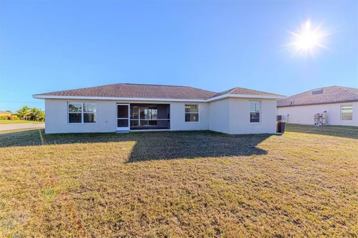 Rear view of property featuring stucco siding and a lawn
