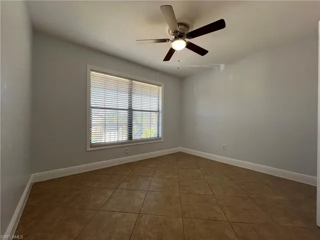 Tiled spare room featuring baseboards and a ceiling fan