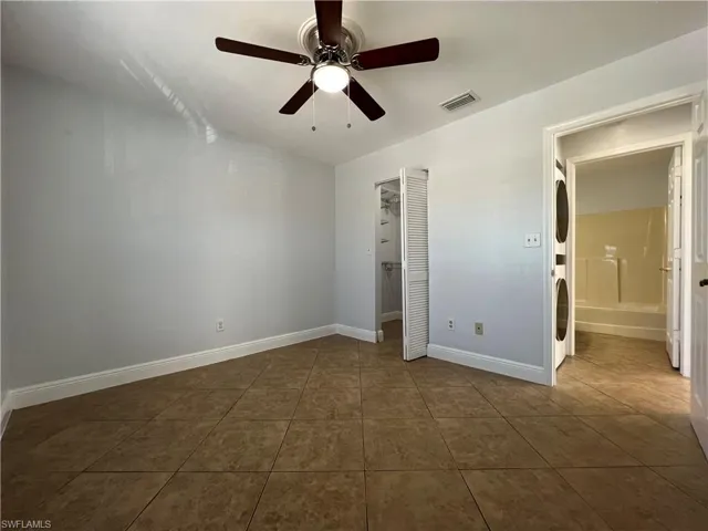 Unfurnished bedroom with a spacious closet, ceiling fan, tile patterned floors, and vaulted ceiling