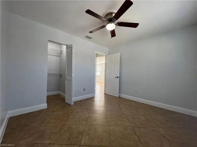 Unfurnished bedroom with a closet, dark tile patterned flooring, and a ceiling fan
