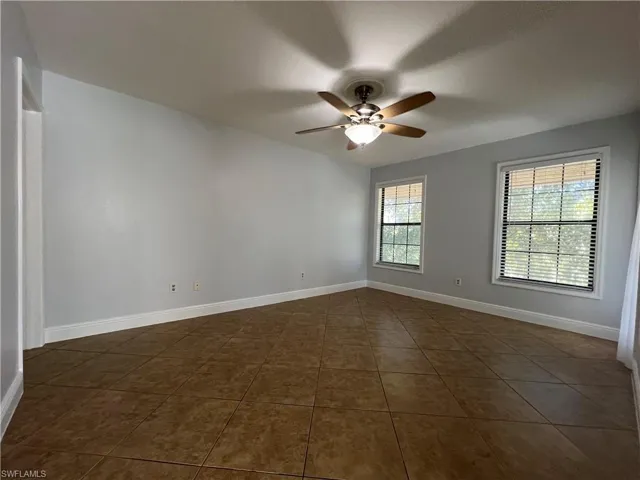 Spare room with a ceiling fan and dark tile patterned flooring