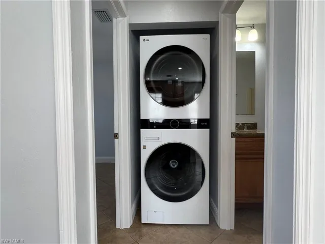 Laundry area with light tile patterned floors and stacked washer and clothes dryer