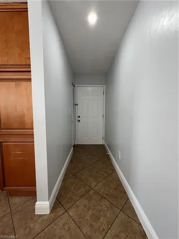 Hall featuring dark tile patterned floors and baseboards