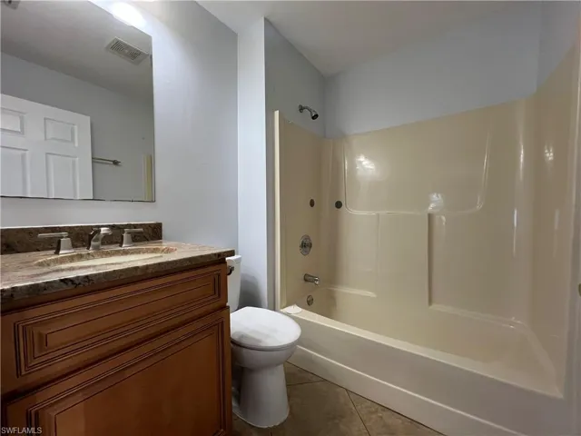 Bathroom featuring shower / bath combination, vanity, and light tile patterned floors