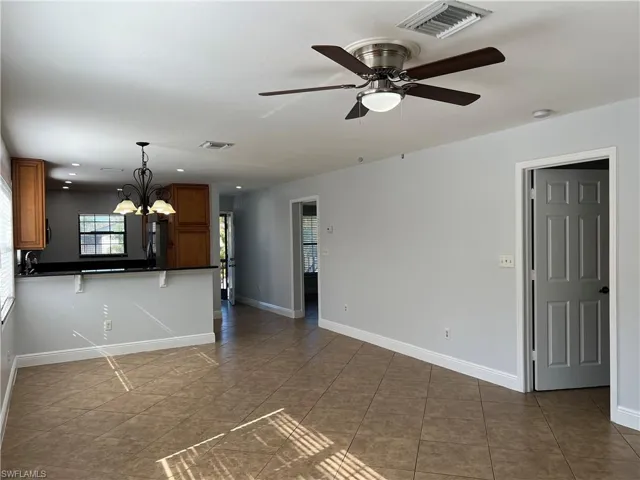 Unfurnished living room with a chandelier, a ceiling fan, and light tile patterned floors